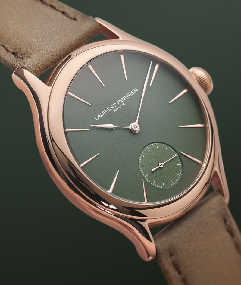 Side close-up shot of the Classic Micro-Rotor 'Evergreen dial' LAURENT FERRIER watch in rose gold and brown leather bracelet against forest green background.