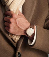 Hand wearing the new Classic Origin Beige with a brown coat and beige scarf