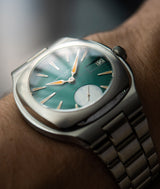 Close-up view of the Sport Auto 40's inclined aperture date window and purple detailing on blue green dial with orange Super Luminova hands and indices.