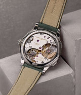 Watch resting on its front on two steps-like concrete blocs exposing the "Série Atelier III" engraving at the top of the back case as well as the LF230.02 Traveller highly hand-finished movement