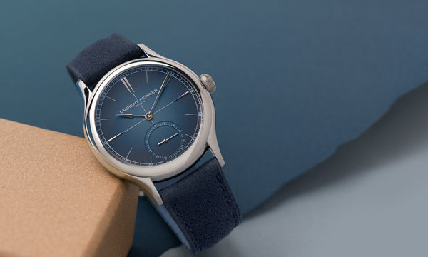 Swiss fine watchmaker's Classic Origin model with gradient navy blue dial with dark blue bracelet, the watch is resting on a tan colored block against a blue teared background. Photographed by Cyril Biselx in Geneva, Switzerland