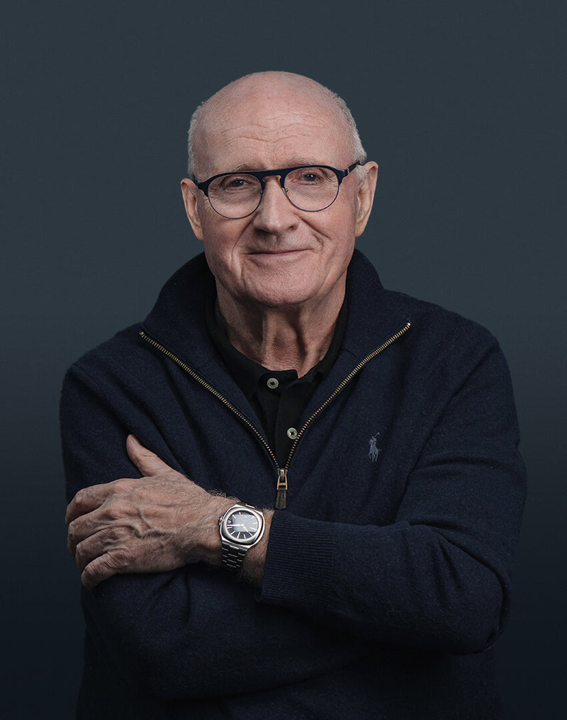 Portrait of smiling brand founder and president François Servanin against blue grey background wearing the Laurent Ferrier original Sport Auto with blue gradient dial. Photographer Cyril Biselx in brand's headquarters Plan-Les-Ouates, Geneva, Switzerland