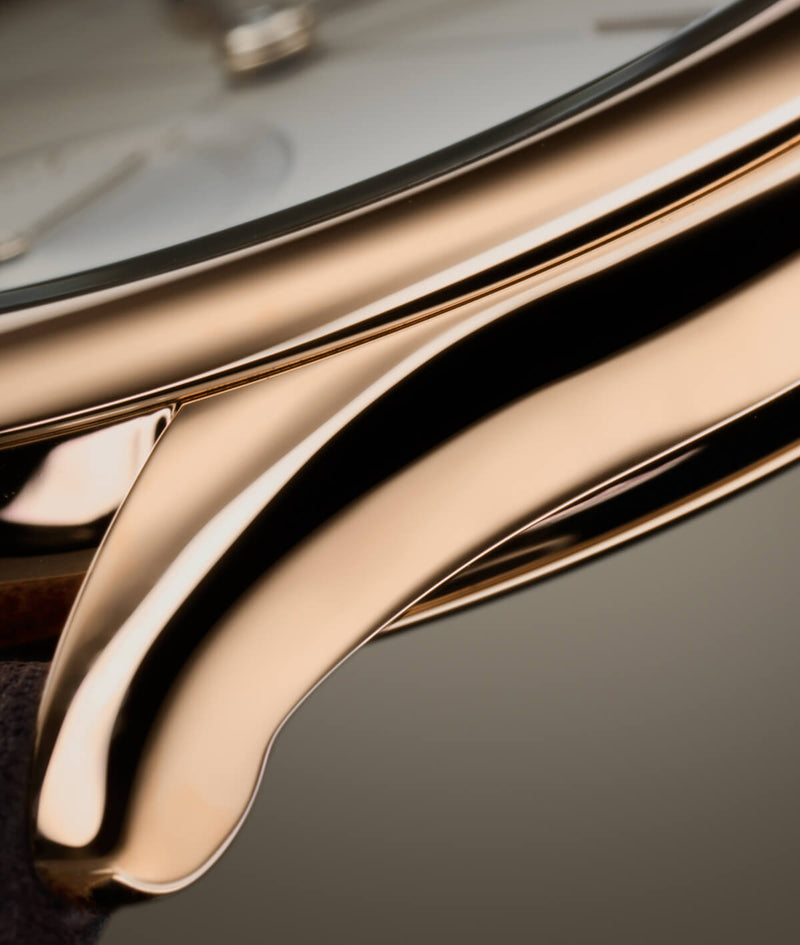 Focus picture on the lug of the warmly toned 18 750 5N red gold case of the new Classic Origin Beige LCF036.R5.BR5 Laurent Ferrier watch on a taupe background. photo by EastImage.