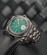  'Lifestyle' advertising front view of the new online exclusive 'Série Atelier – Sport Auto 40' with green dial inspired by Laurent Ferrier's Porsche 935 at the 24h of Le Mans race against metal background, carbon fiber floor and leather pocket. Lightweight titanium highly finished integrated bracelet. Photographed by Cyril Biselx in Switzerland