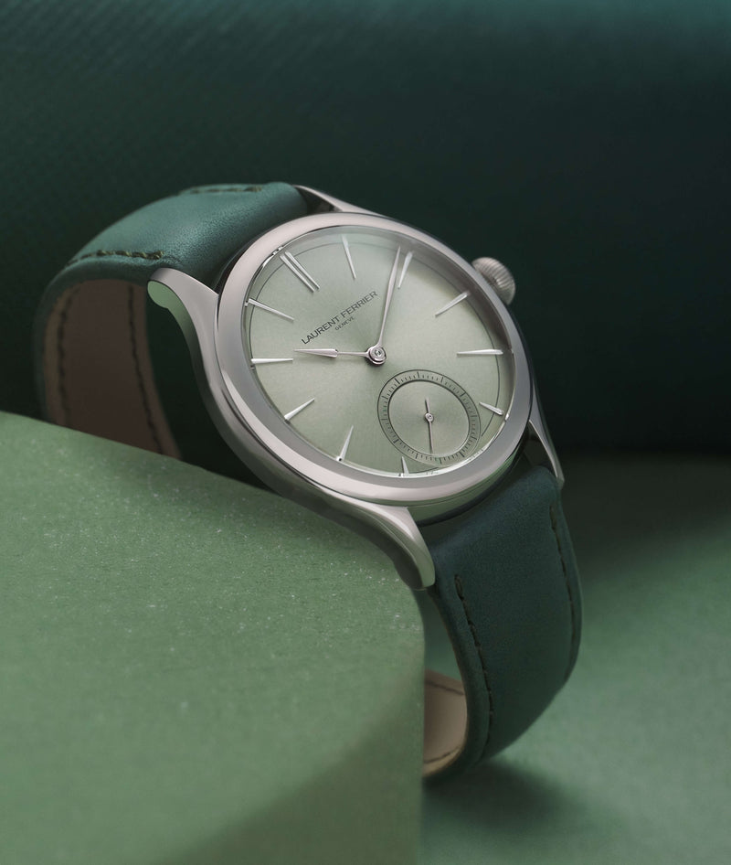 Lifestyle front view of Laurent Ferrier fine watchmaker's Classic Micro-Rotor with "Magnetic Green" reflective dial and forest green bracelet. The watch is resting on a green circle of hard foam against a deep green background. Captured by Cyril Biselx in Geneva, Switzerland