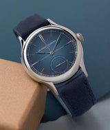 Classic Origin Blue by renowned watchmaker Laurent Ferrier laying on its side on a tan colored block against a blue paper background. Photo Cyril Biselx