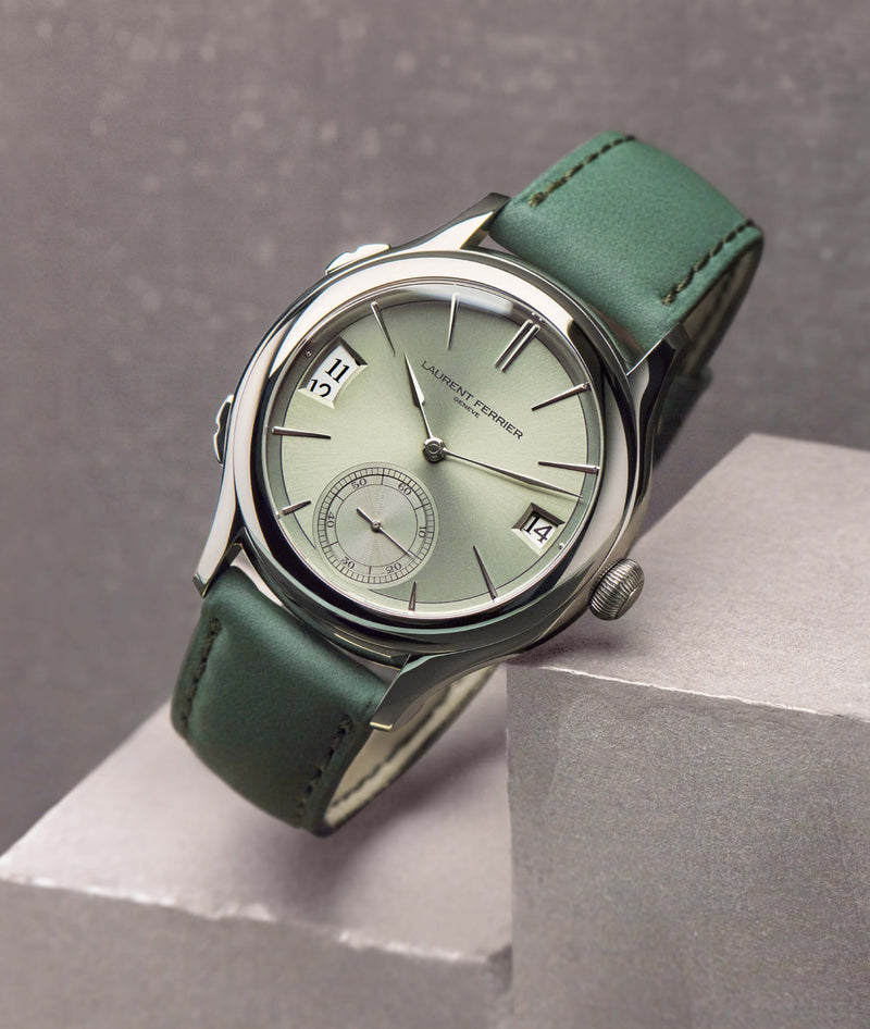 Magnetic green dial watch from swiss fine watchmaker Laurent Ferrier Geneva, it is resting on a concrete cube. The watch features a green lime reflective dial, white-gold assegai hands and indexes and dual-time date windows.