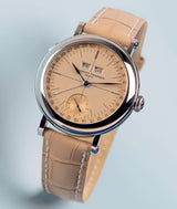 floating laurent ferrier ecole micro rotor vintage yellow gold watch with date and small second on a tan beige alligator bracelet on baby blue background