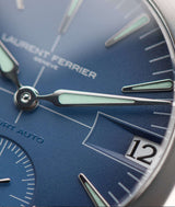 macro close-up of laurent ferrier grand sport blue dial's "guichet" date window featuring a long slope that lets light in.  large "assegai" hand in white gold holds mint green superluminova. photographer cyril biselx