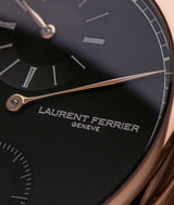 close-up of laurent ferrier square regulateur's red-gold hour assegai-shaped hand and brand's logo stamped in silver on the black dial